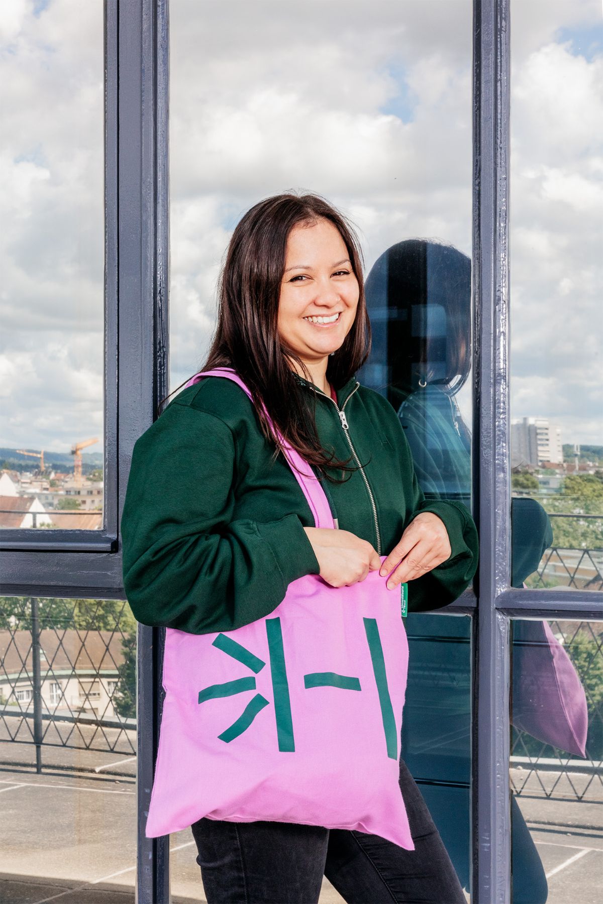Employee with dark green hoodie and pink tote bag USB merchandise